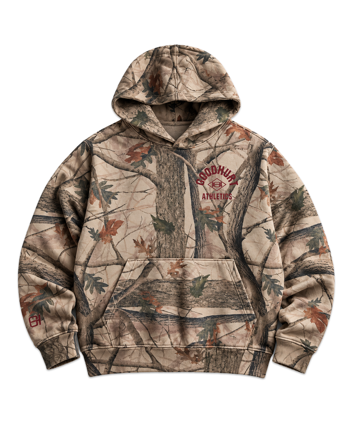 A camouflage pullover hoodie with a realistic woodland tree and leaf print in beige, brown, and green tones, featuring a 'GOOD HURT Athletics' logo on the left chest.
