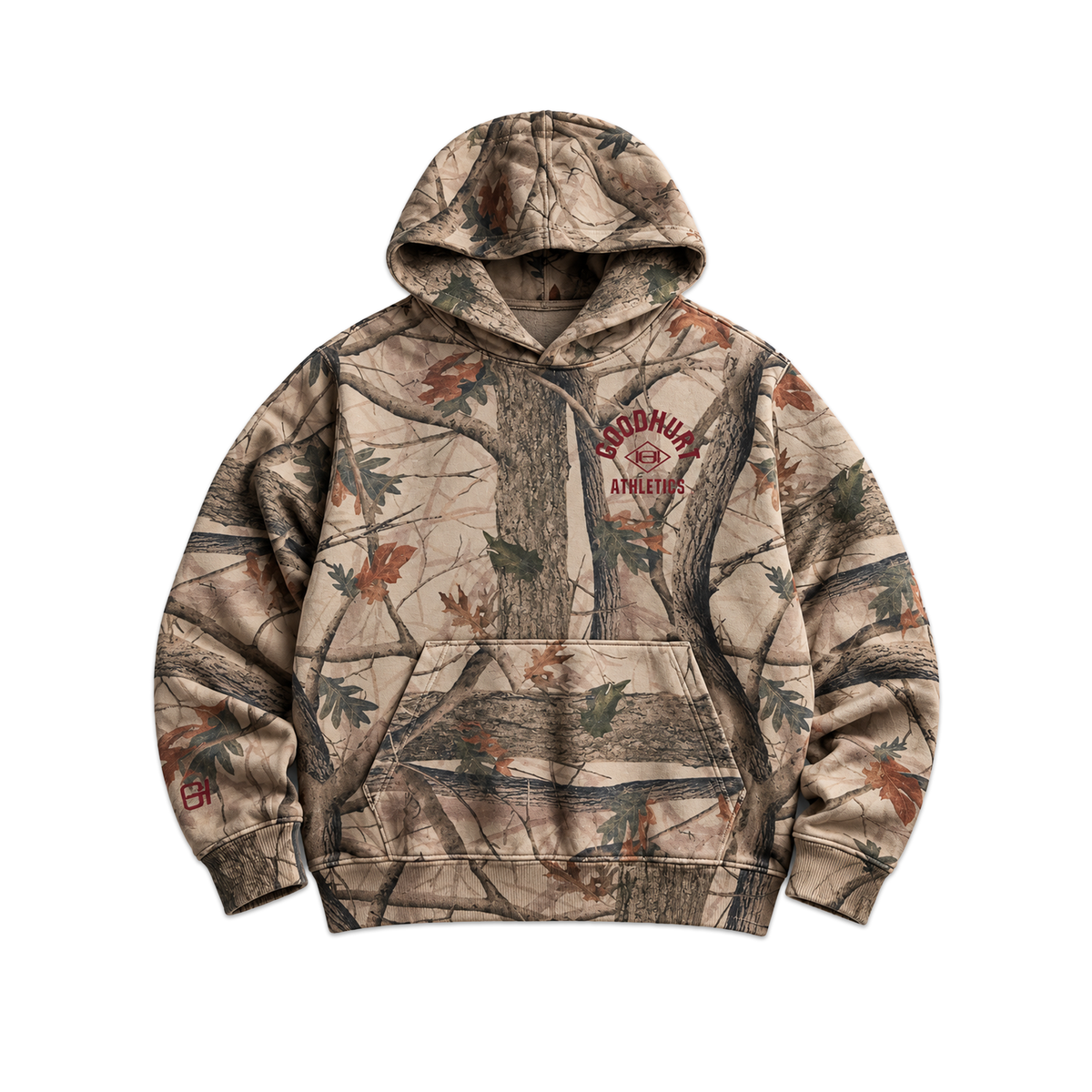 A camouflage pullover hoodie with a realistic woodland tree and leaf print in beige, brown, and green tones, featuring a 'GOOD HURT Athletics' logo on the left chest.