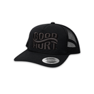 A black trucker hat with a curved brim, black mesh back, and tonal black embroidered 'GOOD HURT' logo on the front. A silver circular sticker on the brim reads 'SNAPBACK'.